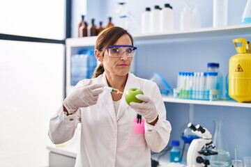 Sticker - Middle age woman working at scientist laboratory with food clueless and confused expression. doubt concept.