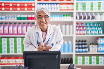 Wall Mural - Middle age woman with tattoos working at pharmacy drugstore smiling and laughing hard out loud because funny crazy joke with hands on body.