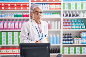 Wall Mural - Middle age woman with tattoos working at pharmacy drugstore with hand on stomach because indigestion, painful illness feeling unwell. ache concept.