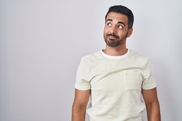 Sticker - Hispanic man with beard standing over isolated background smiling looking to the side and staring away thinking.