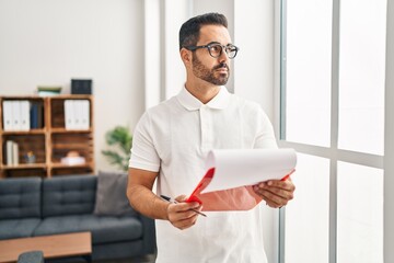 Wall Mural - Young hispanic man psychologist reading report document at psychology center