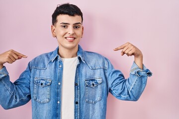 Sticker - Non binary person standing over pink background looking confident with smile on face, pointing oneself with fingers proud and happy.