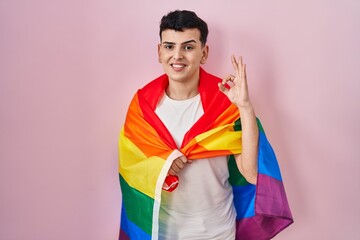 Canvas Print - Non binary person holding rainbow lgbtq flag doing ok sign with fingers, smiling friendly gesturing excellent symbol