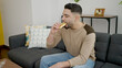 © Krakenimages.com - Young arab man eating cake sitting on sofa at home