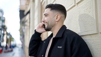 Wall Mural - Young arab man smiling confident talking on the smartphone at street