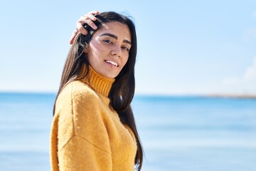 Wall Mural - Young hispanic woman smiling confident standing at seaside