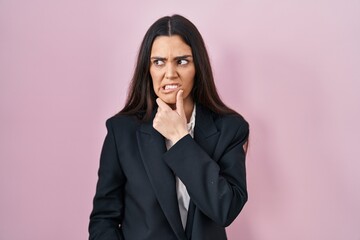 Young brunette woman wearing business style over pink background thinking worried about a question, concerned and nervous with hand on chin