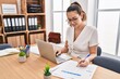 © Krakenimages.com - Young beautiful hispanic woman business worker using laptop writing on document at office