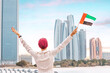 citizen woman stands tall with the UAE flag, exemplifying the strong cultural and historical ties between the UAE and its neighboring Arab countries.