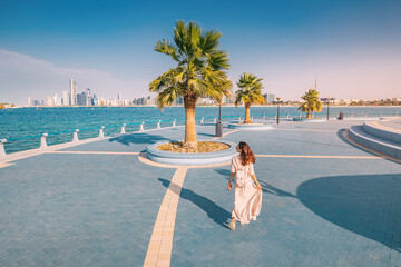 Wall Mural - Walking along the Corniche at sunset is a magical experience, with the warm hues of the sky complementing the sparkling waters of the Gulf and the gleaming towers of the city skyline.