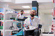 © DC Studio - Portrait of pharmacist holding medical tonometer ready to measure clients hypertension during checkup visit in pharmacy. Drugstore filled with supplements and vitamins, medicine service