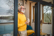 © Miljan Živković - One senior man stand in at door of tiny house happy smile hold cup