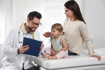 Canvas Print - Mother and her cute baby having appointment with pediatrician in clinic. Doctor examining little girl