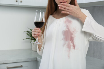 Wall Mural - Embarrassed woman with stain on her clothes and glass of wine indoors, closeup