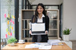 © Natee Meepian - attractive Asian young business woman at her office desk workspace with a notebook laptop computer. Notebook blank screen mockup