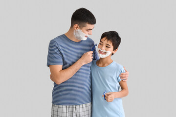 Poster - Father and his little son shaving against light background