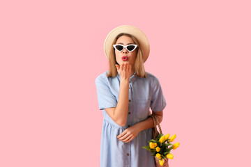 Sticker - Young woman in sunglasses with bag of tulips blowing kiss on pink background