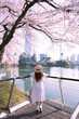 Asian lady travel in cherry blossom park in Seoul city,South Korea with Sakura flower and Lotte World Tower and Seokchon Lake background.