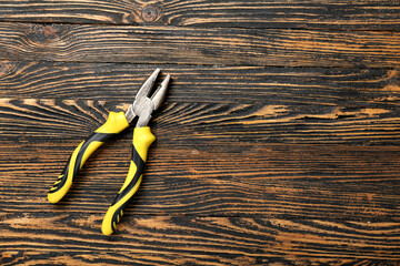 Yellow pliers on wooden background