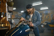 © Nomad_Soul - Mature male biker examining his new motorbike standing with garage