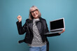 joyful modern 50s mature old lady freelancer with gray hair surfs the internet using laptop with mockup on bright background