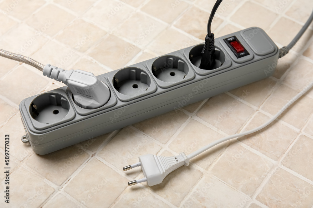 Electric extension cord with plugs on tile background