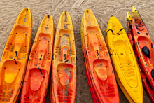 Brightly Coloured Plastic Kayaks Yellow And Red On Sand Beach Coast