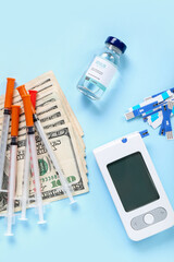 Wall Mural - Insulin with glucometer, lancet pens, syringes and money on blue background. Expensive medicine concept