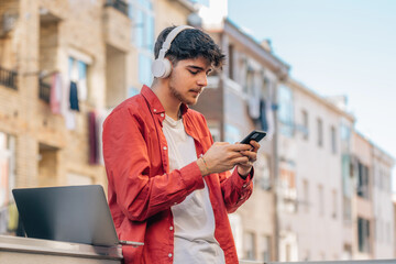 Poster - young man with smartphone or mobile phone and earphones outdoors in the city