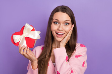 Sticker - Portrait of funny surprised girl brown hair young hold her international woman day heart shape giftbox touch cheek isolated on purple background