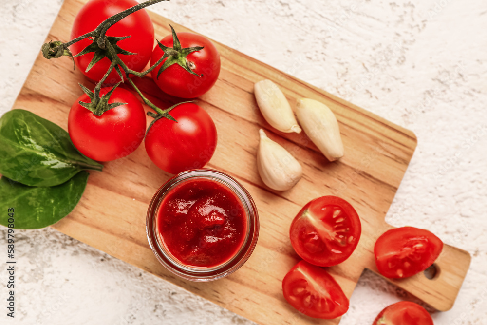 Jar with tasty tomato paste and fresh vegetables on light background