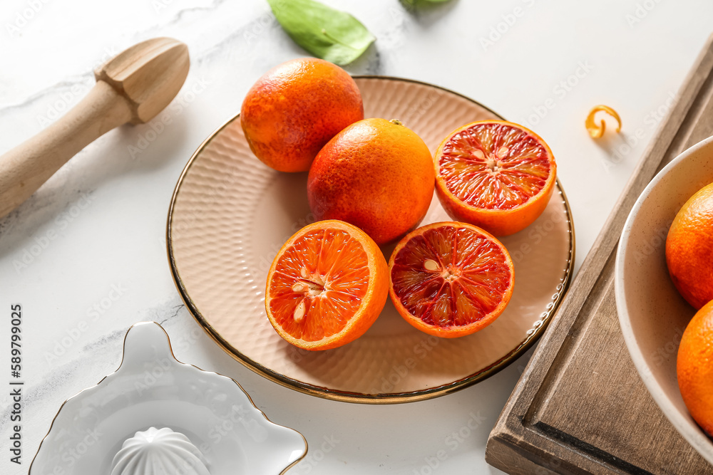 Plate with tasty blood oranges on light background