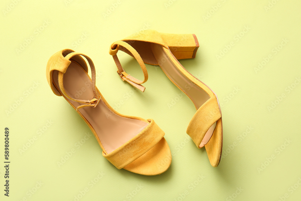 Pair of stylish high heeled sandals on green background