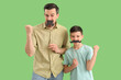 © Pixel-Shot - Portrait of happy father and his little son with paper mustache on green background