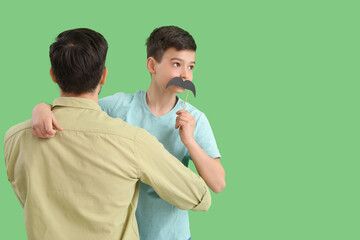 Poster - Father and his little son with paper mustache on green background