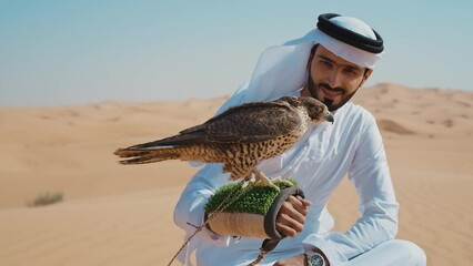 Wall Mural - Falconer training his falcon bird in the desert of Dubai. Locals spending time on the dunes in Sharjah. Concept about traveling in the united arab emirates