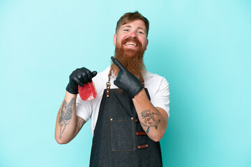 Butcher man wearing an apron and serving fresh cut meat isolated on blue background pointing to the side to present a product