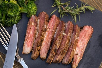 Canvas Print - Closeup shot of sliced roasted beef meat with broccoli put on the black board on the table