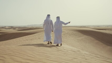 Wall Mural - Two friends making the safari in the Dubai desert. Locals with kandura white outfit spending time together on the dunes in sharjah. Concept about traveling in the united arab emirates