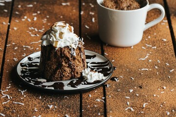 Wall Mural - Closeup shot of a chocolate cake and a white cup on the wooden background