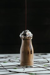 Sticker - Closeup shot of a cute mini glass bottle of chocolate milkshake topped with whipped cream