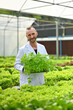 © Prathankarnpap - Portrait of smiling caucasian male scientists holding crate of seedlings standing in industrial greenhouse