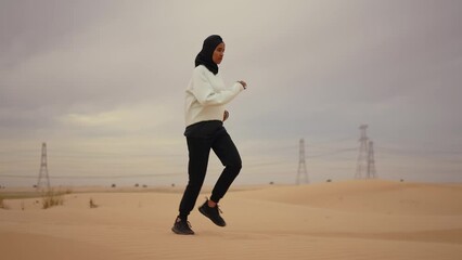 Wall Mural - Beautiful female runner wearing sport abaya running in the desert in dubai, united arab emirates. Concept about sport, and muslim culture