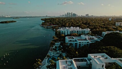 Sticker - Aerial view of a city with green vegetation at the shore at calm sunset