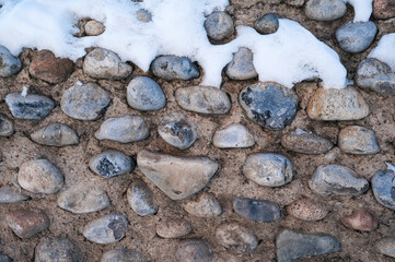 Wall Mural - texture of cobblestone stones in a concrete old wall in winter with snow