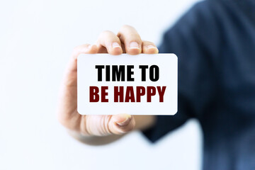 Time to be happy on blank business card being held by a woman's hand with blurred background. Business concept about time to be happy.