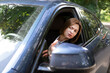 © Vitaliy - Nervous business woman driving and peeps out of the window of her luxury car. Discontented woman in black suit standing in traffic jam and looking out of her car and demonstrating her displeasure