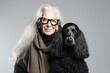 © Trinette Reed - Studio portrait of fashionable senior woman with grey hair and her black poodle dog. They look alike. Generative AI.
