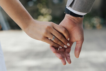 Wall Mural - The young couple in love hold of hands. Close-up.