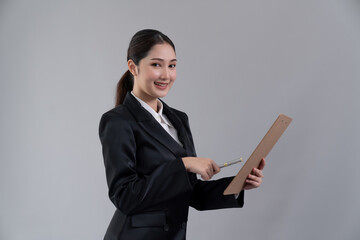 confident young businesswoman stands on isolated background, holding clipboard and posing in formal 
